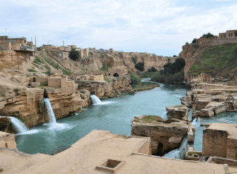 view of the Shushtar Historical Hydraulic System, featuring cascading waterfalls, ancient water mills along the Karun River